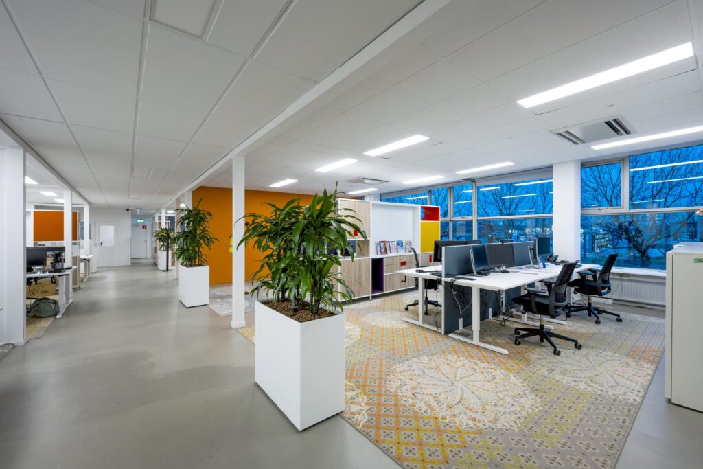 Modern ingericht kantoor aan de Van der Madeweg met open werkplekken, kamerplanten en kleurrijke accenten.